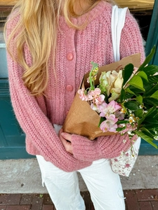 Detail of pink cable knit cardigan with buttons styled with a bouquet of fresh flowers