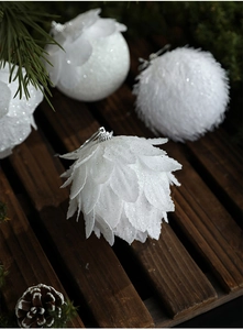 Close-up of white glittery foam Christmas balls with petal textures on dark wood background