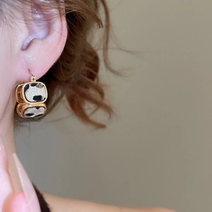 Primo piano di orecchini quadrati placcati in oro 18K con inserto leopardato indossati