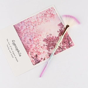 Macro detail of a fan highlighter brush with purple gradient bristles and glitter handle