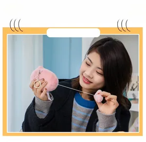 Close-up of pink plush cat keychain showing pull-string kinetic tail function