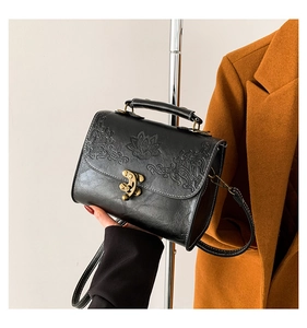 Gros plan détaillé des motifs de lotus gaufrés et du fermoir bronze sur le sac noir