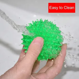 Durable green TPR squeaky dog ball with soft spikes being rinsed under water