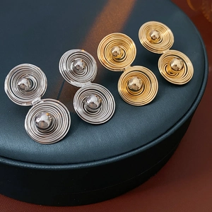 Dettaglio orecchini a disco a doppia spirale oro e argento con sfere metalliche