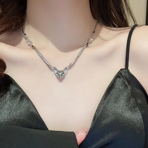 Close-up of cat head pendant necklace with blue gemstone eyes on female neck