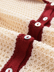 Macro shot of knit texture and pearlescent buttons on red and white knitwear set