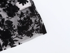 Close-up of black lace shirt showing intricate floral flocking on sheer mesh fabric