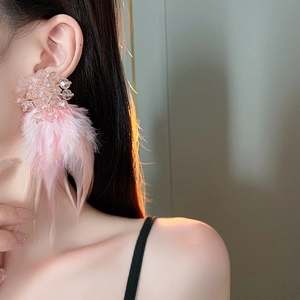 Detailed view of pink feather earrings with crystal flower stud on a female model