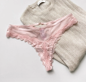 Detailed view of pink lace thong featuring mesh fabric and a silver heart-shaped metal buckle