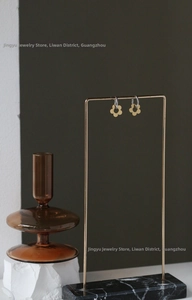 Close-up of daisy petal earrings with gold and silver two-tone finish on a metal stand