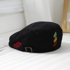 Detail of embroidered beret for kids with safety pin design and metal buckle adjustment
