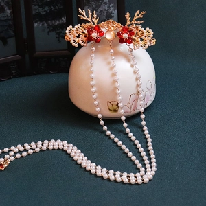 Detail of golden deer antler hairpin with red flowers and long white pearl tassels