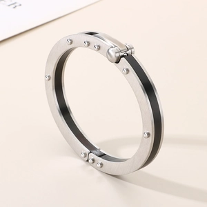 Macro view of brushed stainless steel bracelet with industrial rivets on warm beige background