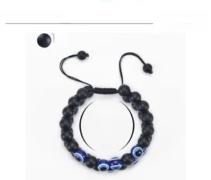 Detail of 10mm matte black stone beads and blue evil eye charms on a woven cord bracelet