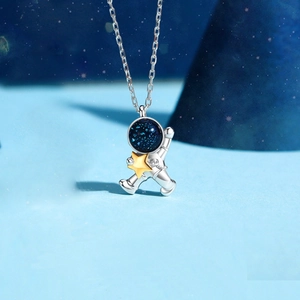 Detail of silver astronaut pendant with blue galaxy visor and gold star necklace
