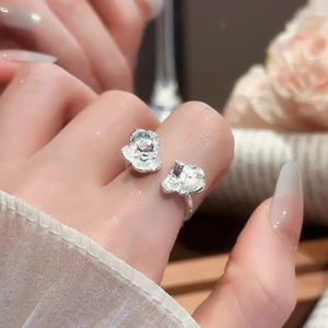 Detail of flower-shaped silver ring with purple rectangular gems on woman's finger