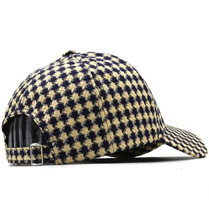 Detail of houndstooth knitted baseball cap with adjustable metal buckle and curved brim