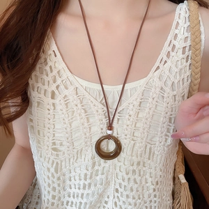 Detailed close-up of a brown resin circle pendant necklace on a white lace top