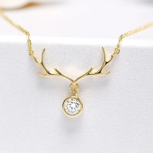 Macro view of golden antler necklace with a round brilliant zircon pendant and cable chain