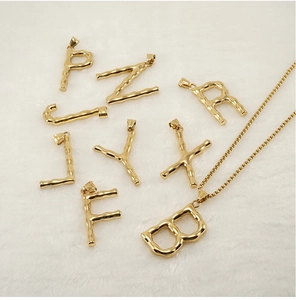Close-up of golden letter pendants with unique bamboo texture on white faux fur