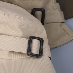 Detail view of the brown leather buckle and fine stitching on a cotton bucket hat side
