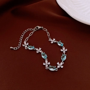 Elegant silver bracelet with oval blue stones and crystal clover links on silk