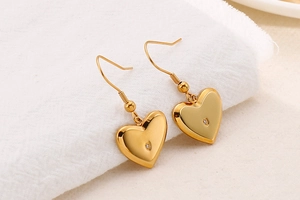 Macro detail of heart-shaped gold earrings with small clear cubic zirconia stone
