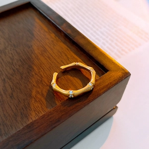 Macro detail of gold bamboo-shaped ring with matte finish and tiny zircon inlays