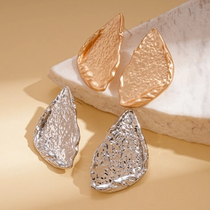 Irregular textured drop earrings in gold and silver finish set on white marble
