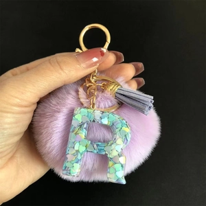 Gros plan du porte-clés lettre R en résine avec pompon violet et sequins en cœur