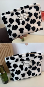 Detail of cow print plush coin purse with zipper and Time to Party textile label
