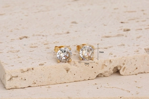 Detail view of 7mm 18K gold-plated cubic zirconia stud earrings on a natural stone surface