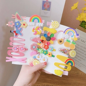 Close-up of colorful macaron hair clips featuring rainbow and fruit motifs for girls