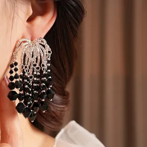 Elegant silver tassel earrings with black faceted glass beads on female model