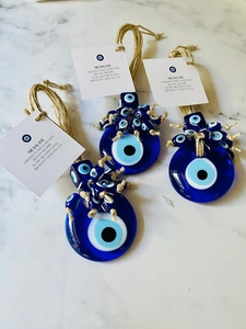 Close-up of three blue glass Evil Eye pendants with rustic jute ropes and blessing labels