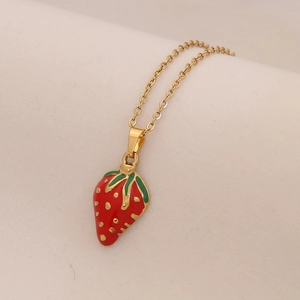 Macro di una collana con ciondolo a fragola in smalto rosso e catena sottile dorata