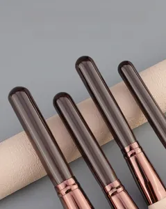 Detail of deep brown wood handle and rose gold metal ferrule on professional makeup brush