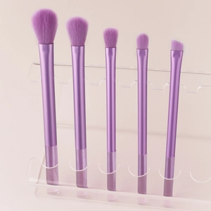 Macro shot of 5 purple makeup brushes with crystal handles on an acrylic stand