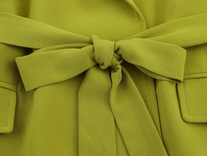 Detailed close-up of textured fabric with a stylish bow belt and rectangular flap pockets