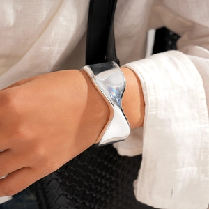 Macro detail of silver wavy metal cuff bracelet showing organic geometric polished texture