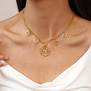 Close-up of golden rose pendant and spiral charms on an O-chain necklace on model