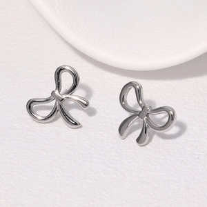 Macro shot of silver bow stud earrings with a polished mirror finish on white background