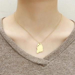 Close-up of golden South Korea map necklace with heart detail worn on a brown sweater