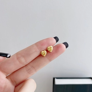 Close-up of yellow heart stud earrings featuring a center gemstone held by hand