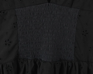 Gros plan sur la broderie florale ajourée noire et la taille élastique plissée sur la robe