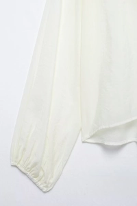 Detailed close-up of cream chiffon blouse featuring elastic cuffs and textured fabric