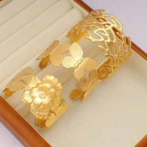 Three-piece set of gold hollow-out cuff bracelets featuring floral and butterfly designs
