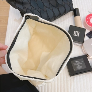 Macro view of canvas toiletry bag featuring geometric pattern and black zipper detail