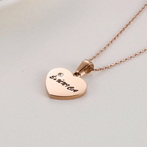 Detail of rose gold heart pendant with crystal inlay and engraved lettering on fine chain
