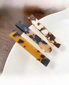 Detailed view of three acetate rectangular hair clips with amber and marble patterns